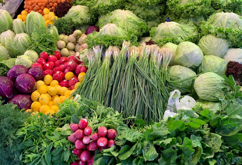 Market stall piled with lettuces, green onions, radishes, lemons and red cabbage